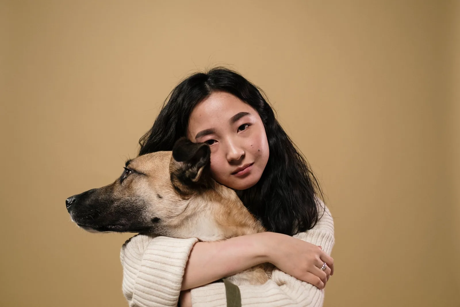 A woman resting her head against her dog in a warm embrace